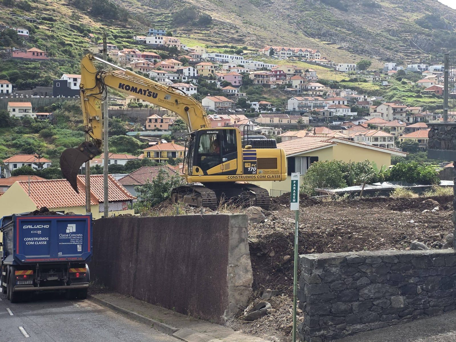 Excavator and truck by the old wall