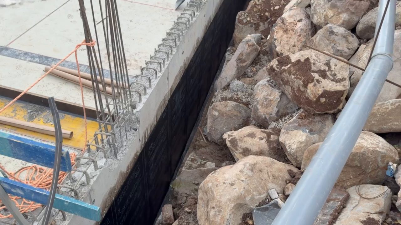 Waterproofed wall, rock fill behind it